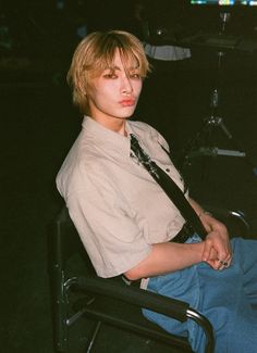 a young man sitting in a chair wearing a tie