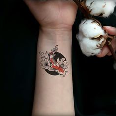 a person with a tattoo on their arm next to some cotton flowers and a branch