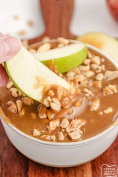 someone is dipping an apple into a bowl of oatmeal with walnuts