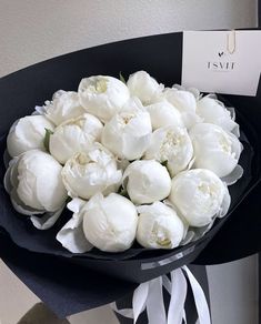 a bouquet of white flowers sitting on top of a black table next to a card