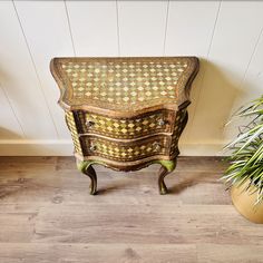 an old wooden dresser next to a potted plant on top of a hard wood floor