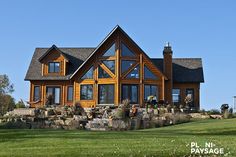 a large wooden house sitting on top of a lush green field