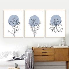 three framed art prints on a wall above a bed in a room with white furniture