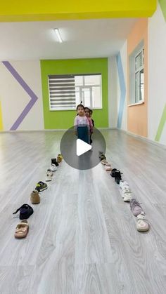 two people standing in an empty room with shoes on the floor and one person taking a photo