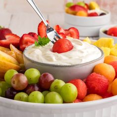 a bowl full of fruit with a fork sticking out of the top and another bowl in the background