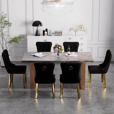 a dining room table with black chairs and a chandelier