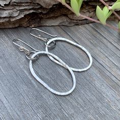 Embrace the charm of rustic elegance with our Riverstone Sterling Silver Dangle Earrings. Handcrafted to showcase the natural beauty of a riverstone shape, these large, oval earrings bring a playful imperfection that adds a casual yet sophisticated touch to any look. Made from sterling silver, they’re perfect for everyday wear, adding an artisanal flair to both casual and bohemian styles. Thoughtfully designed, these earrings are an ideal choice for those who appreciate unique, timeless accessor Everyday Hammered Oval Jewelry, Everyday Oval Hammered Jewelry, Nickel Free Oval Minimalist Earrings, Nickel-free Oval Minimalist Earrings, Minimalist Nickel-free Oval Earrings, Rustic Silver Oval Jewelry, Handmade Rustic Oval Jewelry, Everyday Bohemian Oval Jewelry, Nickel-free Oval Teardrop Earrings