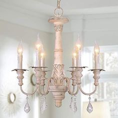 a chandelier hanging from the ceiling in a living room with white walls and windows