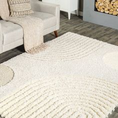 a living room with a couch, chair and rug in front of a fire place