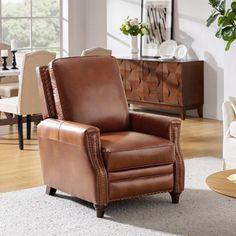 a brown leather recliner chair sitting in a living room next to a white rug