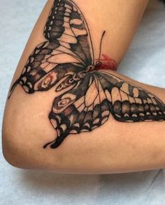 a woman's leg with a butterfly tattoo on the side and an apple in her lap