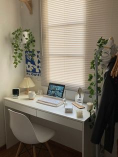 a white desk topped with a laptop computer next to a window