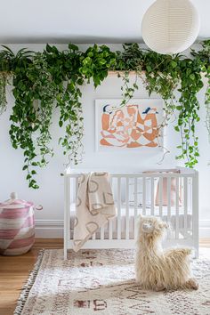 a white crib with plants on the wall and a dog sitting in front of it