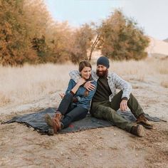 a man and woman sitting on top of a blanket