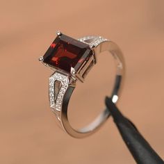 It is a natural garnet ring. The main stone is 7 mm*9 mm emerald cut.weight about 3.04 carats.The basic metal is sterling silver and plated with rhodium.To change the metal to a solid gold (white/rose) or platinum is also available, please ask for a quotation if you want.You can also go to my shop Home for more elegant rings: https://www.etsy.com/shop/godjewelry?ref=hdr_shop_menu Garnet is January birthstone More garnet rings:https://www.etsy.com/shop/godjewelry?ref=seller-platform-mcnav&sec Emerald Cut Ruby Ring With Accent Stones As Gift, Classic Emerald Cut Ruby Ring As Gift, Classic Garnet Jewelry With Halo Setting, Elegant Garnet Birthstone Ring With Center Stone, Classic Emerald-cut Sterling Silver Birthstone Ring, Classic Emerald Cut Sterling Silver Birthstone Ring, Classic Emerald-cut Birthstone Ring In Sterling Silver, Classic Emerald Cut Birthstone Ring In Sterling Silver, Classic Garnet Diamond Ring Gift