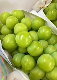 green grapes are in white bowls with spoons next to them and a cd on the table