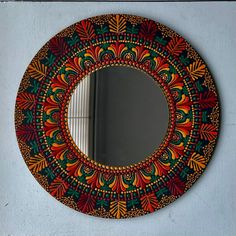 a round mirror hanging on the side of a wall with an artistic design painted on it