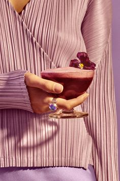 a woman holding a drink in her hand with a flower on the top of it