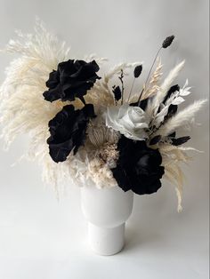 a white vase filled with black and white flowers