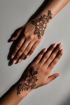 two hands with henna tattoos on them