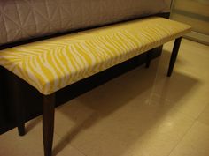 a yellow bench sitting on top of a white tiled floor