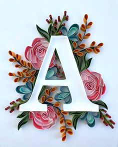 the letter a made out of paper with flowers and leaves on it, in front of a