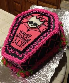 a pink and black birthday cake sitting on top of a table