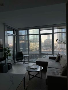 a living room filled with furniture and large windows overlooking cityscape in the distance