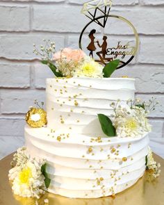 a white wedding cake with gold sprinkles and flowers