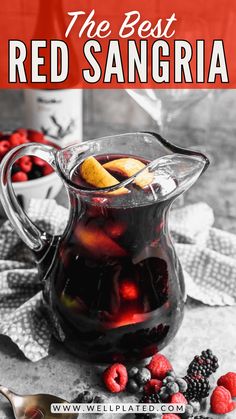 a pitcher filled with red sangria sitting on top of a table next to berries