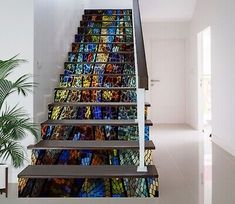 a stair case with stained glass windows on the side and bottom, along with a potted plant