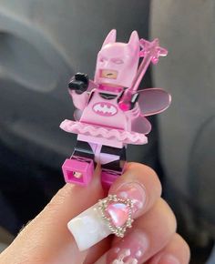 a hand holding a pink lego batman doll