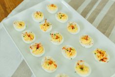 small deviled eggs are arranged on a white platter, ready to be eaten