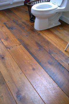 a white toilet sitting on top of a wooden floor