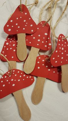 red and white mushrooms are hanging from clothes pins on a string with jumbo sticks