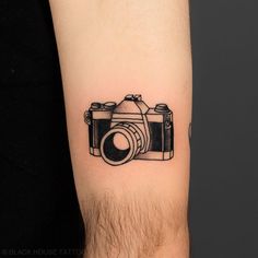 a black and white photo camera tattoo on the arm