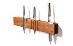 five knives are hanging on a wall mounted knife holder