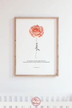 a pink rose is hanging on the wall above a crib with a baby's name