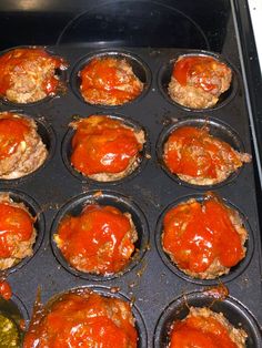 an oven filled with muffins covered in marinara sauce and meat patties