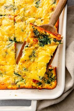 a square casserole with cheese and spinach on top, cut into squares