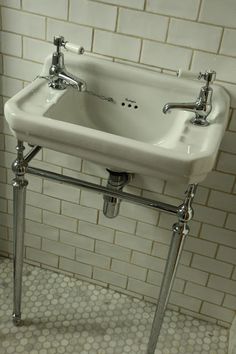 a white sink sitting on top of a metal stand