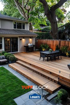 a backyard deck with patio furniture and landscaping in the foreground, next to a large tree