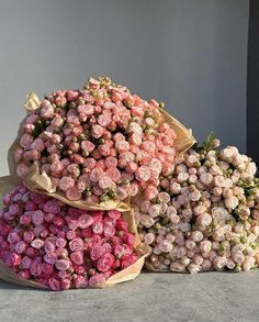 three large bouquets of pink roses sitting on top of each other in front of a gray wall