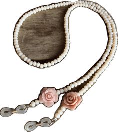 a white leash with pink flowers and pearls on it's end, hanging from the side