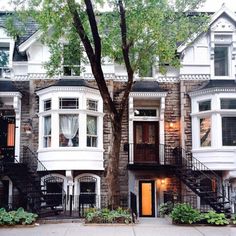 an apartment building with many windows and balconies on the second floor, next to a tree