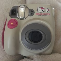 a hello kitty camera sitting on top of a white blanket