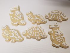 six decorated cookies sitting on top of a white table next to an orange and black cat