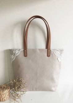 a white purse sitting on top of a table next to a vase with flowers in it