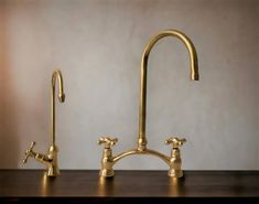 two brass faucets on a wooden table