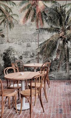 a table and chairs in front of a wall with palm trees